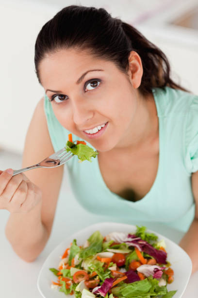 istock Young woman eating salad 855604860
