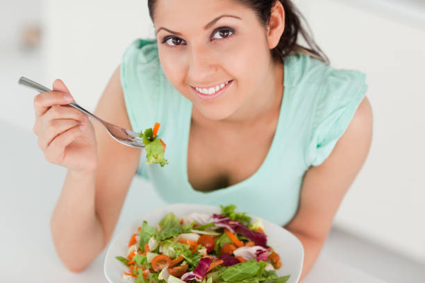 istock Cute young woman eating salad 855605142