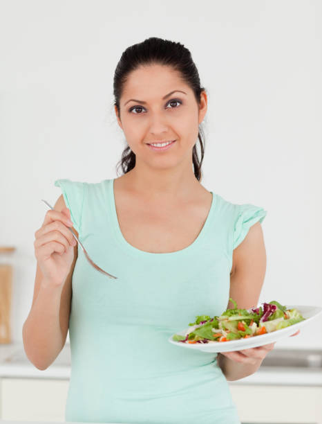 istock Young woman standing in kitchen with salad 855608014