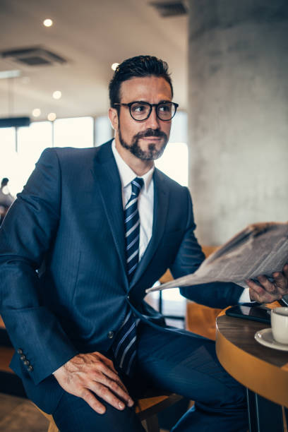 istock Businessman reading newspaper in coffee shop 855611048