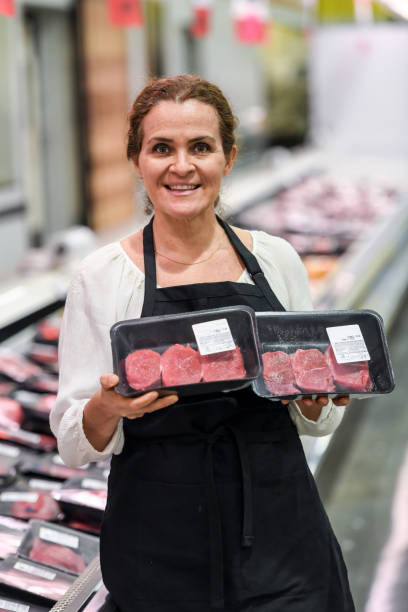 working at the supermarket meat department - supermarket meat store manager imagens e fotografias de stock