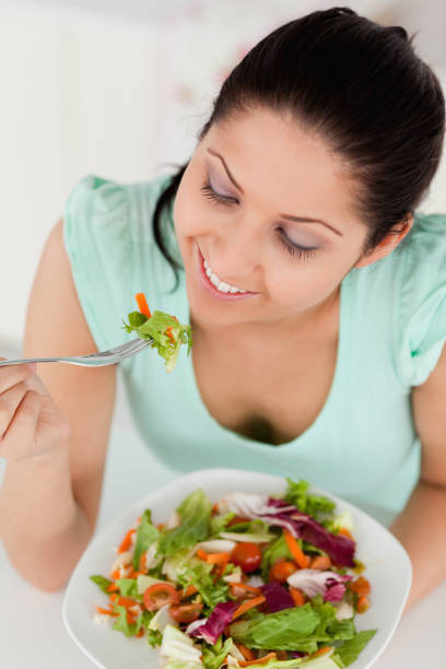 istock Smiling young female eating salad 855611796