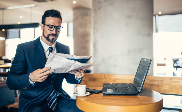 istock Businessman reading newspaper in cafe 855611912