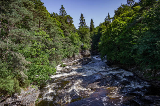 istock View of a rushing stream, forest and small cottage in Invermoriston 855614228