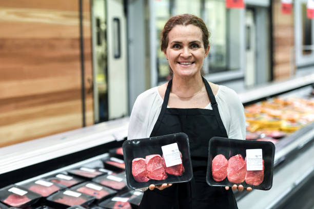 working at the supermarket meat department - supermarket meat store manager imagens e fotografias de stock