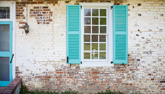 Closeup of front window of historic colonial home in Yorktown Virginia, USA; mint, turqoise, distressed brick