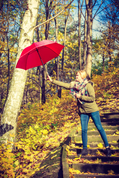 istock Woman walking in park with umbrella, strong wind 855632328