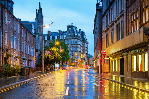 Stock photograph of a colorful street with hotel and businesses in downtown Dundee, Scotland, United Kingdom on a rainy evening.