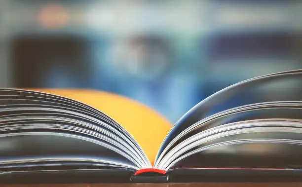 Open book on working desk in the library room with blurred focus for business and education background