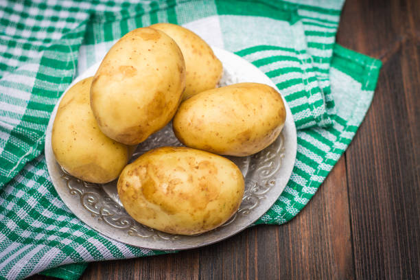 istock Raw potatoes on a brown wooden background 855651114