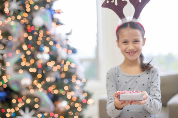 istock A young ethnic girl delightedly holds open a wrapped present 855651384