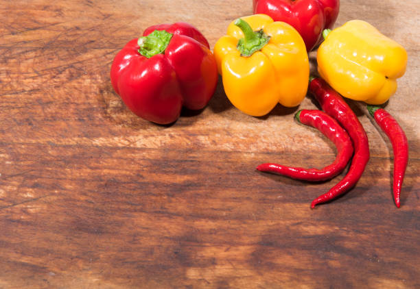 Colored bell peppers and red peppers on wooden background.