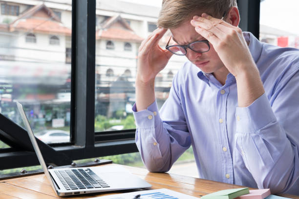 istock tired businessman with hand on forehead at office. frustrated man with headache at workplace. exhausted startup business owner in depression after long work. overwork, stress, fatigue concept 855654486