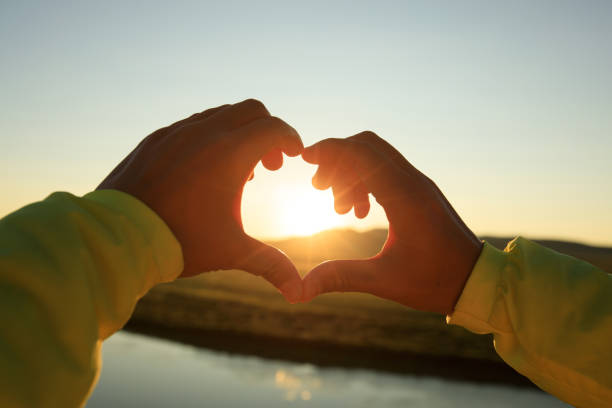 istock Human hands making Heart shaped sign over sunset sky 855657586