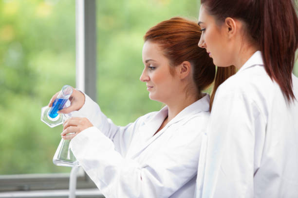 istock Young scientists pouring liquid in an Erlenmeyer flask 855663488