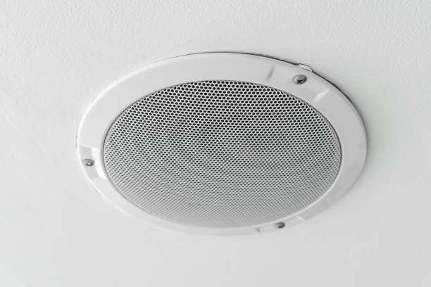 White round circle speaker and grille hanging on white ceiling stock photo