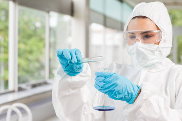 Protected female scientist pouring liquid Protected female scientist pouring liquid in a laboratory scientific exploration stock pictures, royalty-free photos & images