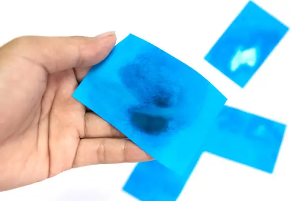 Women hand holding blue Oil absorbing blotting sheets to remove excess oil on oily face  on white background.