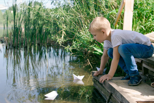 istock A boy with a paper boat by the river. 855672032