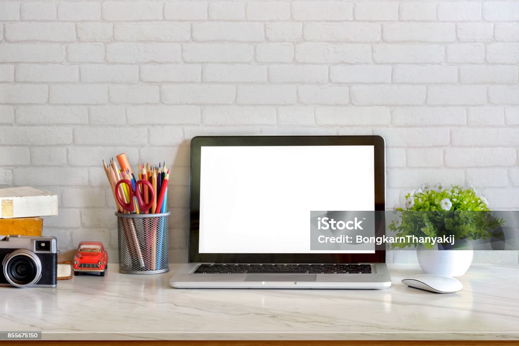 Stylish workspace with supplies. desk space concept. Front view picture of studio workplace with blank screen laptop and supplies. Designer comfortable work table, home studio office. Computer Monitor Stock Photo