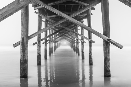 A black and white photo of a pier in the fog