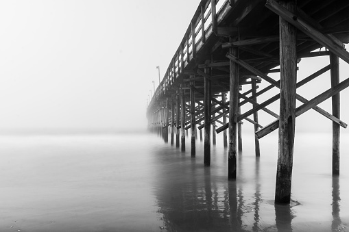 A black and white photo of a pier in the fog