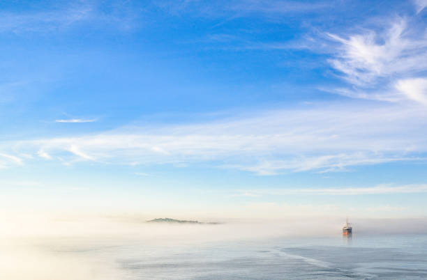 A boat cuts through the fog on a weather heavy morning in Canada, Nova Scotia, Halifax