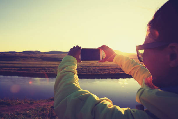 istock taking photo with smart phone in beautiful sunset landscape 855687548