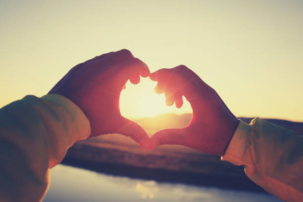istock Human hands making Heart shaped sign over sunset sky 855688094