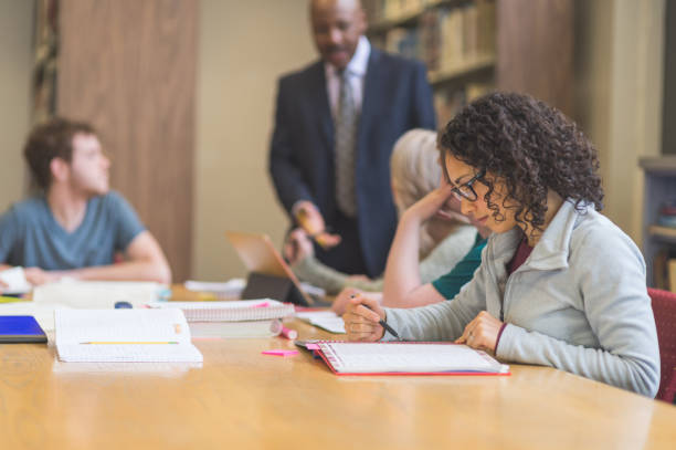 istock College students study together in the university library. An African American professor is helping them. 855690506