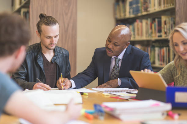 istock College students study together in the university library. An African American professor is helping them. 855690510