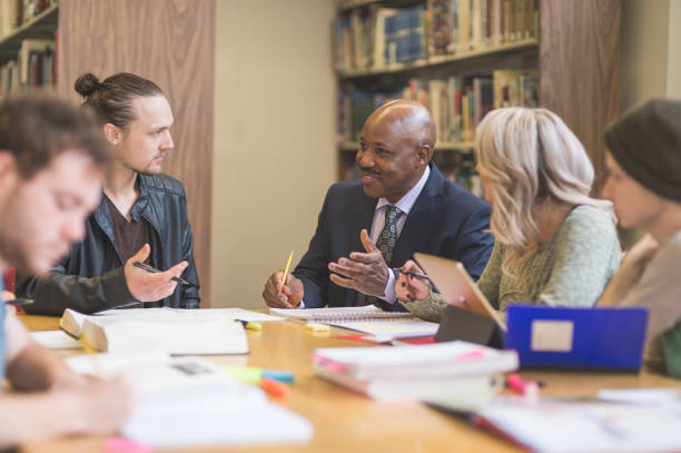 istock College students study together in the university library. An African American professor is helping them. 855690518