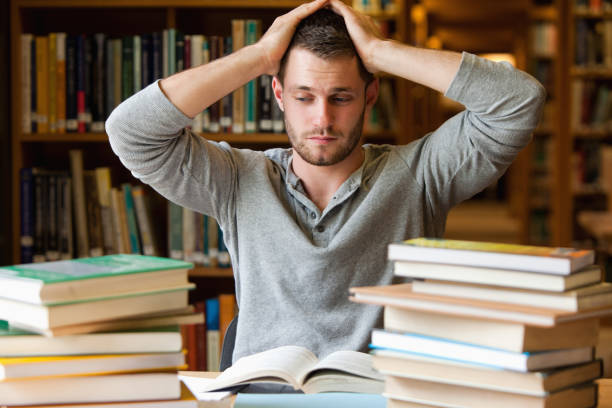 Tired student having too much to do Tired student having too much to do in a library quiz time stock pictures, royalty-free photos & images