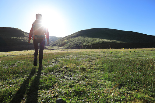 backpacking woman hiker hiking in sunrise mountains