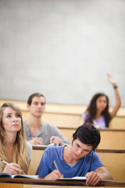 istock Portrait of students taking notes while their classmate is raising her hand 855711360
