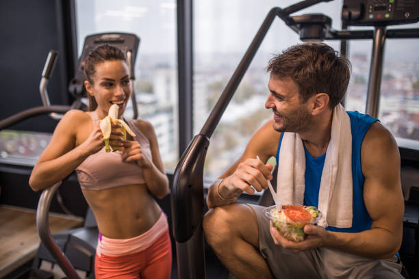 heureux couple athlétique, manger des aliments sains sur une pause dans un gymnase. - sport food exercising eating photos et images de collection