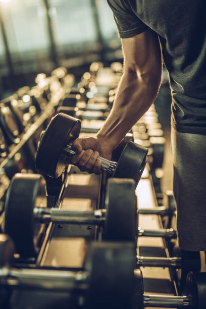 istock Unrecognizable muscular build athlete taking dumbbell from the rack. 855725526