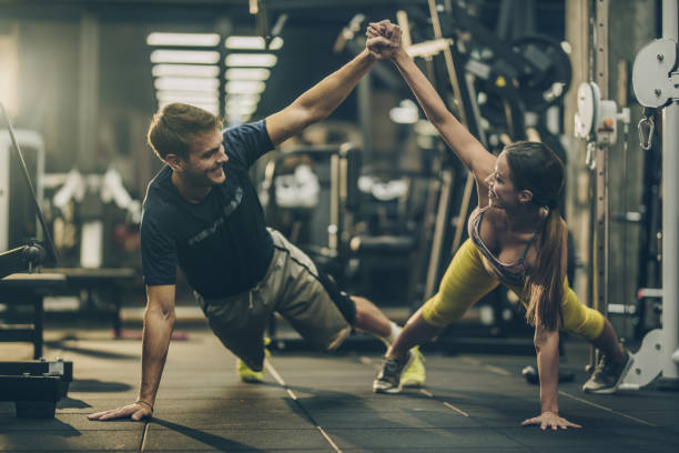 istock Happy athletic couple holding hands while doing push-ups in a gym. 855728584