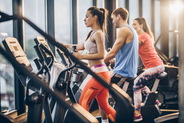 istock Three athletic people warming up on exercise machines in a gym. 855730116