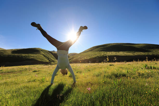 woman doing a handstand in a sunrise meadow