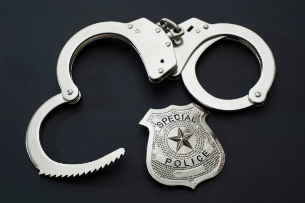 Police badge and handcuffs on black background stock photo