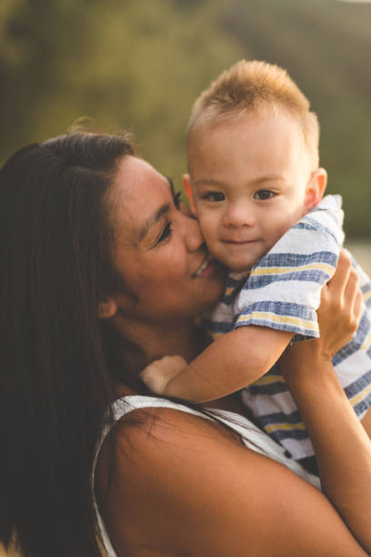 istock Eurasian mother holding adorable son along sandy Hawaii beach 855758632