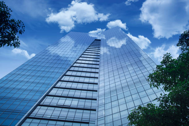 istock Perspective and underside angle view to textured background of modern glass building skyscrapers over blue cloudy sky 855760866