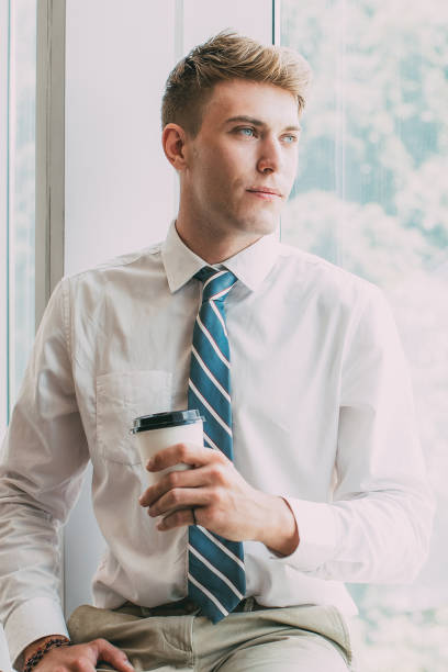 istock Content Business Man on Window Sill With Drink 855775664