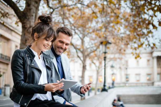 秋のシーズン、ロンドンのトラファルガー広場でデジタル タブレットを使用して美しいカップル - travel destinations outdoors tourist uk ストックフォトと画像