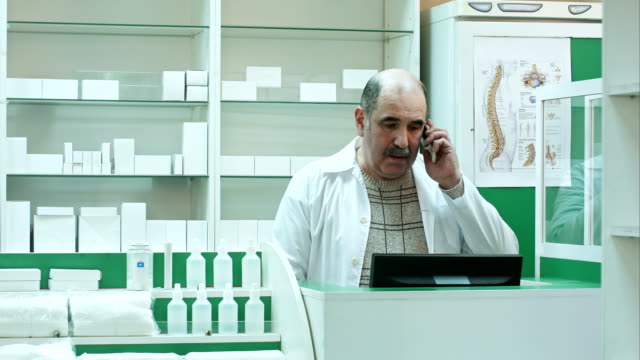 Pharmacist talk with client using mobile phone in pharmacy