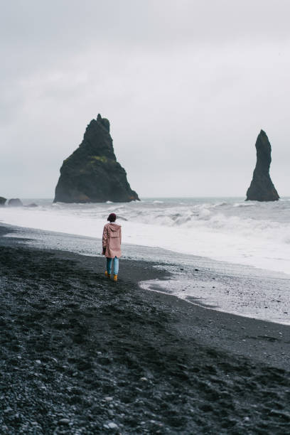 istock Woman walking on the black sand beach in Vik, Iceland 855778952
