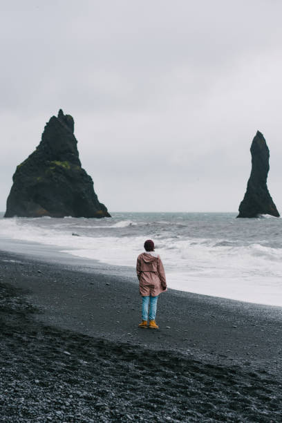 istock Woman walking on the black sand beach in Vik, Iceland 855778956