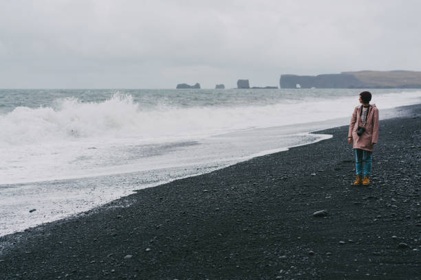 istock Woman walking on the black sand beach in Vik, Iceland 855778958