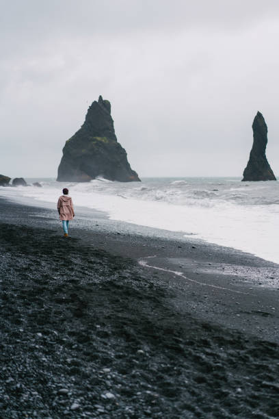 istock Woman walking on the black sand beach in Vik, Iceland 855778994